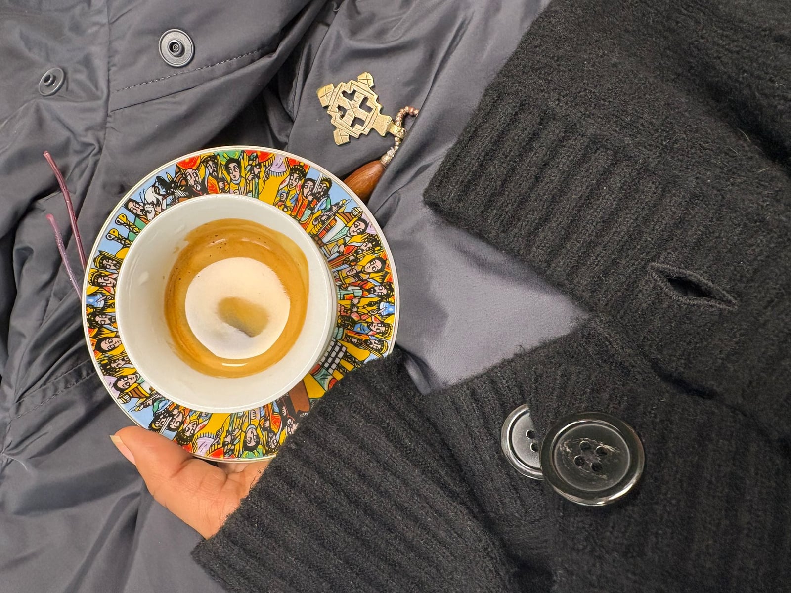 Tasse cini tenue en main avec croix éthiopienne